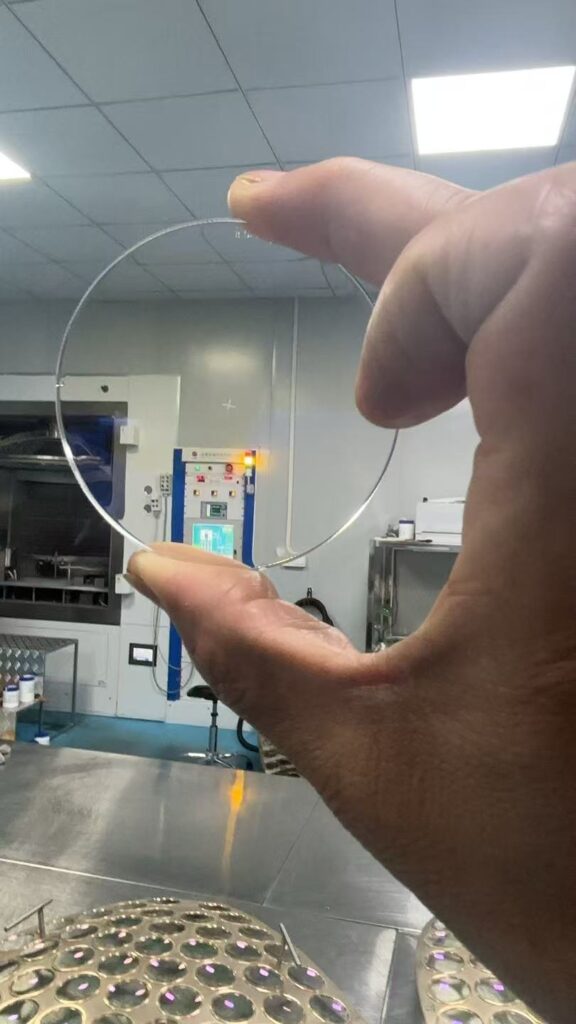 Double-sided AR coated JGS2 quartz glass window for drone sensors, held in YOUJIA OPTICAL coating workshop.